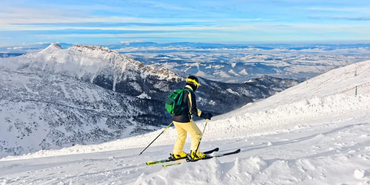 Narciarz zjeżdża po ośnieżonych stokach narciarskich Zakopane, podziwiając malowniczy krajobraz Tatr.